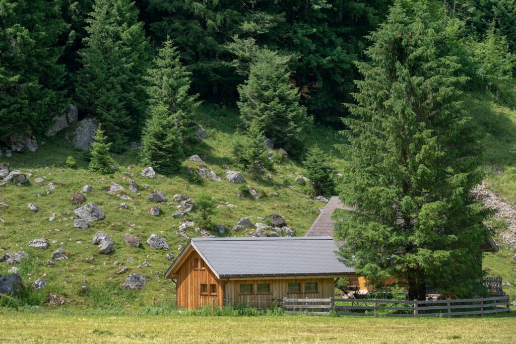 A serene wooden cabin surrounded by dense green forest and rocky terrain, perfect for nature retreats.
